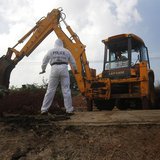 A police officer watches as an excavator digs up skeletons at a construction site in the former war zone in Mannar, about 327 km (203 miles) A police officer watches as an excavator digs up skeletons at a construction site in the former war zone in Mannar, about 327 km (203 miles)