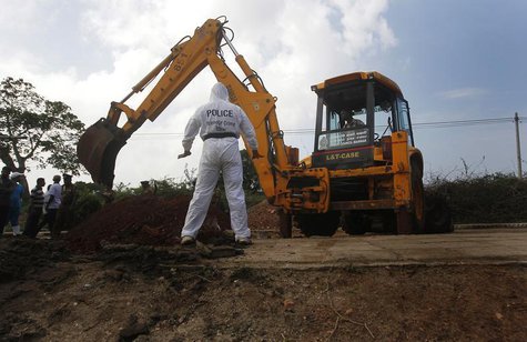 A police officer watches as an excavator digs up skeletons at a construction site in the former war zone in Mannar, about 327 km (203 miles) A police officer watches as an excavator digs up skeletons at a construction site in the former war zone in Mannar, about 327 km (203 miles)