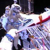 Russian astronaut Oleg Kotov holds an Olympic torch as he takes it on a spacewalk as Russian astronaut Sergei Ryazansky gives instructions o Russian astronaut Oleg Kotov holds an Olympic torch as he takes it on a spacewalk as Russian astronaut Sergei Ryazansky gives instructions o