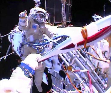 Russian astronaut Oleg Kotov holds an Olympic torch as he takes it on a spacewalk as Russian astronaut Sergei Ryazansky gives instructions o Russian astronaut Oleg Kotov holds an Olympic torch as he takes it on a spacewalk as Russian astronaut Sergei Ryazansky gives instructions o