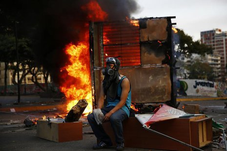 An anti-government protester sits next to a burning kiosk during a protest at Altamira square in Caracas March 9, 2014. REUTERS/Jorge Silva An anti-government protester sits next to a burning kiosk during a protest at Altamira square in Caracas March 9, 2014. REUTERS/Jorge Silva