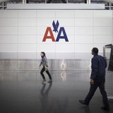 People walk past an American Airlines logo on a wall at John F. Kennedy (JFK) airport in in New York November 27, 2013. REUTERS/Carlo Allegr People walk past an American Airlines logo on a wall at John F. Kennedy (JFK) airport in in New York November 27, 2013. REUTERS/Carlo Allegr