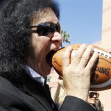 Musician Gene Simmons of rock band KISS bites a football after a news conference to announce his part-ownership of Arena Football League tea Musician Gene Simmons of rock band KISS bites a football after a news conference to announce his part-ownership of Arena Football League tea