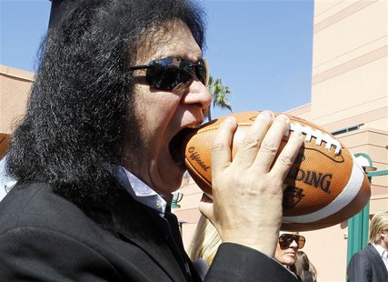 Musician Gene Simmons of rock band KISS bites a football after a news conference to announce his part-ownership of Arena Football League tea Musician Gene Simmons of rock band KISS bites a football after a news conference to announce his part-ownership of Arena Football League tea