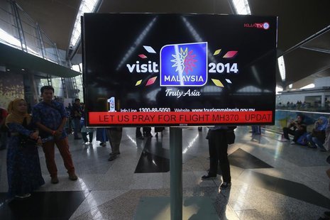An information screen displays a message "Let Us Pray For Flight MH370", regarding the missing Malaysia Airlines flight, at Kuala Lumpur Int An information screen displays a message "Let Us Pray For Flight MH370", regarding the missing Malaysia Airlines flight, at Kuala Lumpur Int