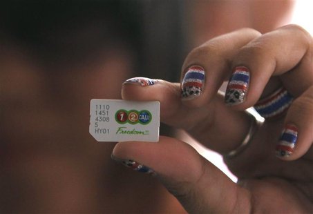 An anti-government protester holds up a sim card before cancelling their AIS subscription during a rally at the Shinawatra building in centr An anti-government protester holds up a sim card before cancelling their AIS subscription during a rally at the Shinawatra building in centr