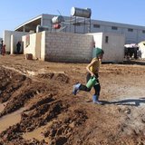A Syrian refugee girl carries a watering can as she walks on mud at the Bab Al-Salam refugee camp in Azaz, near the Syrian-Turkish border Fe A Syrian refugee girl carries a watering can as she walks on mud at the Bab Al-Salam refugee camp in Azaz, near the Syrian-Turkish border Fe