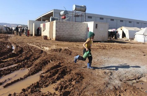 A Syrian refugee girl carries a watering can as she walks on mud at the Bab Al-Salam refugee camp in Azaz, near the Syrian-Turkish border Fe A Syrian refugee girl carries a watering can as she walks on mud at the Bab Al-Salam refugee camp in Azaz, near the Syrian-Turkish border Fe
