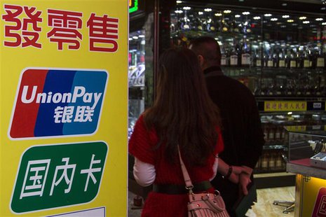 Chinese visitors walk past a sign for China UnionPay outside a pawnshop in Macau, in this picture taken November 20, 2013. REUTERS/Tyrone Si Chinese visitors walk past a sign for China UnionPay outside a pawnshop in Macau, in this picture taken November 20, 2013. REUTERS/Tyrone Si