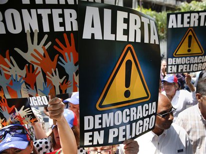 Anti-government protesters hold placards during a gathering against Nicolas Maduro's government outside the Embassy of Portugal in Caracas M Anti-government protesters hold placards during a gathering against Nicolas Maduro's government outside the Embassy of Portugal in Caracas M