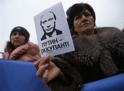 A woman holds a sign with a portrait of Russian President Vladimir Putin and the words "Putin - Occupant" during a pro-Ukrainian rally in Si A woman holds a sign with a portrait of Russian President Vladimir Putin and the words "Putin - Occupant" during a pro-Ukrainian rally in Si