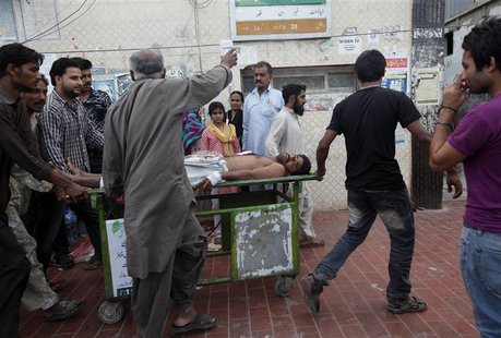 Rescue workers and relatives wheel an injured man on a stretcher, who was attacked by unknown gunmen, at Civil Hospital in Karachi March 12, Rescue workers and relatives wheel an injured man on a stretcher, who was attacked by unknown gunmen, at Civil Hospital in Karachi March 12,