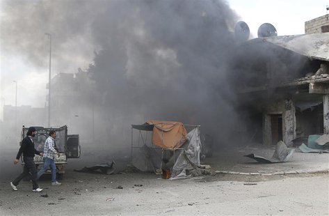 Men walk at a site hit by what activists said were barrel bombs dropped by forces loyal to Syria's President Bashar al-Assad in Aleppo's al- Men walk at a site hit by what activists said were barrel bombs dropped by forces loyal to Syria's President Bashar al-Assad in Aleppo's al-
