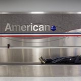 A man sleeps on a conveyer belt under an American Airlines logo at John F. Kennedy International Airport in New York January 22, 2014. REUTE A man sleeps on a conveyer belt under an American Airlines logo at John F. Kennedy International Airport in New York January 22, 2014. REUTE