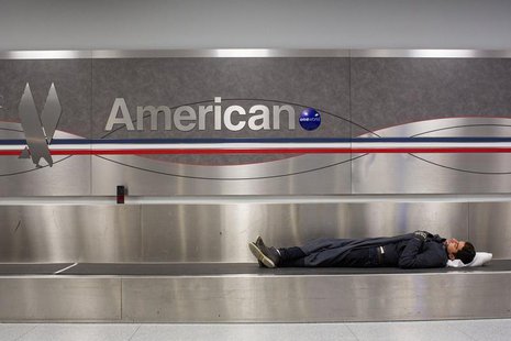 A man sleeps on a conveyer belt under an American Airlines logo at John F. Kennedy International Airport in New York January 22, 2014. REUTE A man sleeps on a conveyer belt under an American Airlines logo at John F. Kennedy International Airport in New York January 22, 2014. REUTE