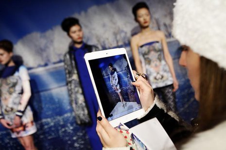 A woman takes a photo of models presenting creations from the Clover Canyon Autumn/Winter 2013 collection during New York Fashion Week, Febr A woman takes a photo of models presenting creations from the Clover Canyon Autumn/Winter 2013 collection during New York Fashion Week, Febr