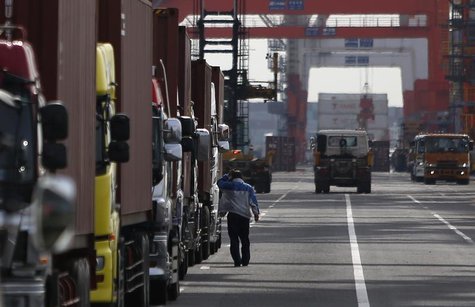 A worker scratching his head walks next to trucks parked inside a container area at a port in Tokyo February 20, 2014. REUTERS/Yuya Shino A worker scratching his head walks next to trucks parked inside a container area at a port in Tokyo February 20, 2014. REUTERS/Yuya Shino