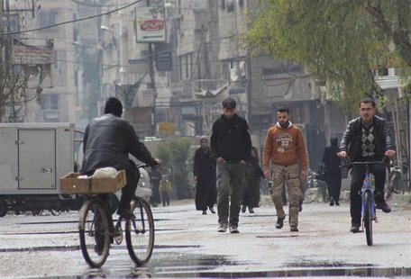 People walk as others ride on a bicycle along a street in Arbeen, in the eastern Damascus suburb of Ghouta, March 9, 2014. Picture taken Mar People walk as others ride on a bicycle along a street in Arbeen, in the eastern Damascus suburb of Ghouta, March 9, 2014. Picture taken Mar