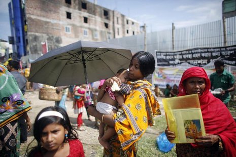 A garment worker who survived the Rana Plaza building collapse, carries her child during a protest to demand for compensation, on the six mo A garment worker who survived the Rana Plaza building collapse, carries her child during a protest to demand for compensation, on the six mo