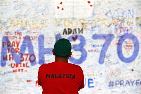 A man stands in front of a board with messages of hope and support for the passengers of the missing Malaysia Airlines MH370 at the departur A man stands in front of a board with messages of hope and support for the passengers of the missing Malaysia Airlines MH370 at the departur