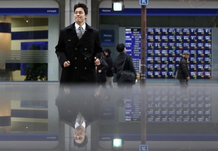 Pedestrians pass by an electronic board displaying stock prices, which are reflected in a polished stone surface, in Tokyo March 7, 2014. RE Pedestrians pass by an electronic board displaying stock prices, which are reflected in a polished stone surface, in Tokyo March 7, 2014. RE