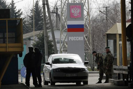 Civilians entering Ukraine (L) have their passports checked as Ukrainian border guards (R) stand at a Russian-Ukrainian border crossing near Civilians entering Ukraine (L) have their passports checked as Ukrainian border guards (R) stand at a Russian-Ukrainian border crossing near