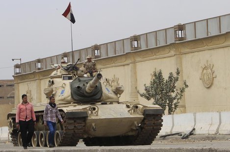 People walk past an Egyptian army tank positioned outside Cairo's Tora prison, March 23, 2014. REUTERS/Mohamed Abd El Ghany People walk past an Egyptian army tank positioned outside Cairo's Tora prison, March 23, 2014. REUTERS/Mohamed Abd El Ghany