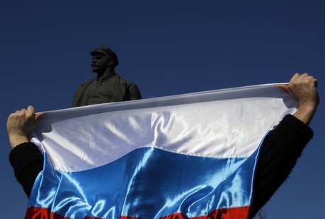 A pro-Russian activist lifts a Russian flag in front of a statue of Lenin during a rally in Donetsk's Lenin square March 23, 2014. REUTERS/Y A pro-Russian activist lifts a Russian flag in front of a statue of Lenin during a rally in Donetsk's Lenin square March 23, 2014. REUTERS/Y