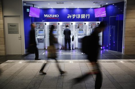 A man uses an ATM machine of Mizuho Bank as pedestrians walk past at a train station in Tokyo November 13, 2013. REUTERS/Yuya Shino A man uses an ATM machine of Mizuho Bank as pedestrians walk past at a train station in Tokyo November 13, 2013. REUTERS/Yuya Shino