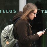 A woman uses a mobile device while walking past a Telus store in Ottawa February 19, 2014. REUTERS/Chris Wattie A woman uses a mobile device while walking past a Telus store in Ottawa February 19, 2014. REUTERS/Chris Wattie