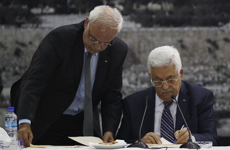 Palestinian chief negotiator Saeb Erekat (L) helps Palestinian President Mahmoud Abbas as he signs international conventions during a meetin Palestinian chief negotiator Saeb Erekat (L) helps Palestinian President Mahmoud Abbas as he signs international conventions during a meetin