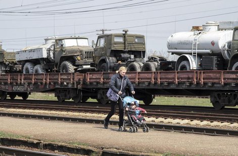 A woman walks with a pram along Ukrainian army vehicles on freight carriages ready to be sent from Crimea in the settlement of Gvardeiskoye A woman walks with a pram along Ukrainian army vehicles on freight carriages ready to be sent from Crimea in the settlement of Gvardeiskoye