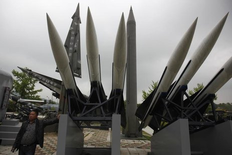 A visitor poses for a photo next to a display of mock South Korean U.S.-made Hawk surface-to-air missiles and a mock North Korean Russian-ma A visitor poses for a photo next to a display of mock South Korean U.S.-made Hawk surface-to-air missiles and a mock North Korean Russian-ma