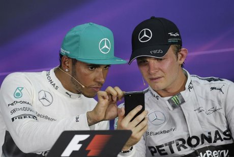 Race winner Mercedes Formula One driver Lewis Hamilton of Britain looks at the mobile device of team mate second-placed Nico Rosberg of Germ Race winner Mercedes Formula One driver Lewis Hamilton of Britain looks at the mobile device of team mate second-placed Nico Rosberg of Germ