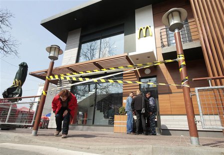 A woman makes her way under a barrier tape outside a McDonald's restaurant, which was earlier closed for clients, in the Crimean city of Sim A woman makes her way under a barrier tape outside a McDonald's restaurant, which was earlier closed for clients, in the Crimean city of Sim