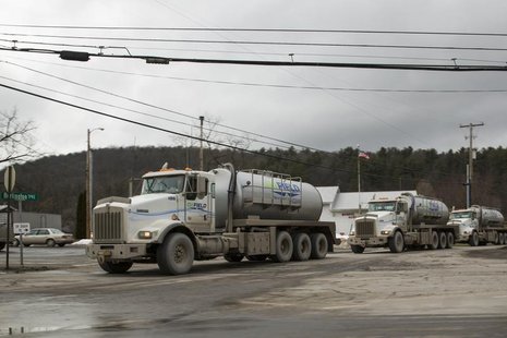 A line of trucks carrying water to Natural gas rigs make their way across the sprawling network of two lane roads between small towns to mak A line of trucks carrying water to Natural gas rigs make their way across the sprawling network of two lane roads between small towns to mak