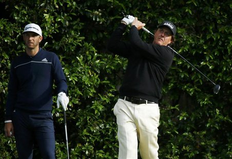 U.S. golfer Phil Mickelson (R) tees off on the fifth hole as compatript Dustin Johnson watches during a practice round ahead of the Masters U.S. golfer Phil Mickelson (R) tees off on the fifth hole as compatript Dustin Johnson watches during a practice round ahead of the Masters