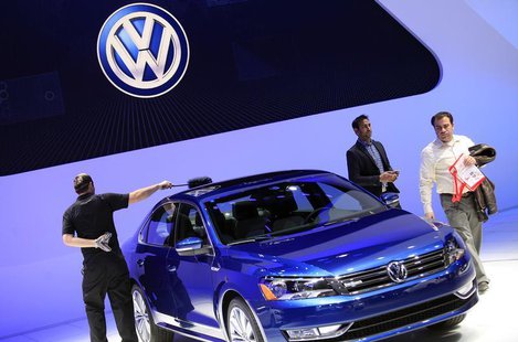 A worker dusts a Volkswagen Passat Blue Motion Concept as visitors look on during the North American International Auto Show in Detroit, Mic A worker dusts a Volkswagen Passat Blue Motion Concept as visitors look on during the North American International Auto Show in Detroit, Mic