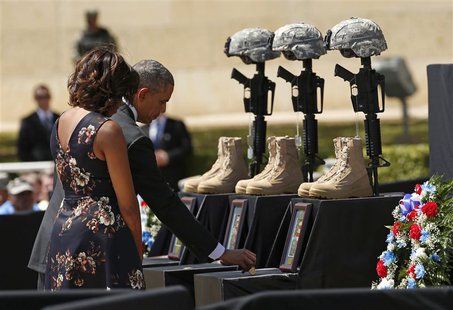 U.S. President Barack Obama places a challenge coin on a memorial as he and first lady Michelle Obama pay their respects for the dead soldie U.S. President Barack Obama places a challenge coin on a memorial as he and first lady Michelle Obama pay their respects for the dead soldie