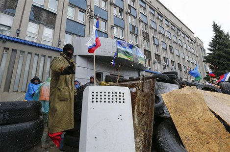 A pro-Russian protester gestures as he stands guard at a barricade in front of the seized office of the SBU state security service in Luhans A pro-Russian protester gestures as he stands guard at a barricade in front of the seized office of the SBU state security service in Luhans