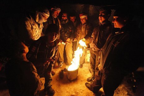 Syrian refugees from the town of Qara gather around a fire to keep themselves warm in a Syrian refugee camp on the Lebanese border town of A Syrian refugees from the town of Qara gather around a fire to keep themselves warm in a Syrian refugee camp on the Lebanese border town of A