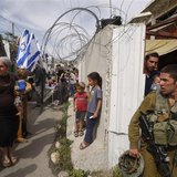An Israeli soldier stand guard as settlers move into a house disputed over by Israeli settlers and Palestinians in the West Bank city of Heb An Israeli soldier stand guard as settlers move into a house disputed over by Israeli settlers and Palestinians in the West Bank city of Heb