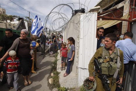 An Israeli soldier stand guard as settlers move into a house disputed over by Israeli settlers and Palestinians in the West Bank city of Heb An Israeli soldier stand guard as settlers move into a house disputed over by Israeli settlers and Palestinians in the West Bank city of Heb