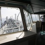 An officer uses binoculars as he stands on a tanker carrying liquefied natural gas in the Mediterranean, some 10 km (6 miles) from the coast An officer uses binoculars as he stands on a tanker carrying liquefied natural gas in the Mediterranean, some 10 km (6 miles) from the coast