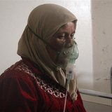 A woman, affected by what activists say was a gas attack, breathes through an oxygen mask inside a field hospital in Kfar Zeita village in t A woman, affected by what activists say was a gas attack, breathes through an oxygen mask inside a field hospital in Kfar Zeita village in t