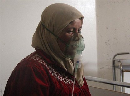 A woman, affected by what activists say was a gas attack, breathes through an oxygen mask inside a field hospital in Kfar Zeita village in t A woman, affected by what activists say was a gas attack, breathes through an oxygen mask inside a field hospital in Kfar Zeita village in t