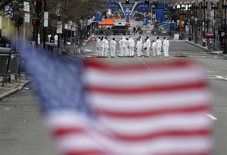 Law enforcement evidence technicians are seen behind a U.S. flag placed at a memorial for the victims as they continue to search the scene o Law enforcement evidence technicians are seen behind a U.S. flag placed at a memorial for the victims as they continue to search the scene o