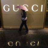 A woman holding an umbrella walks past a company logo of a Gucci boutique outside a shopping mall amid rainfall in central Guangzhou, Guangd A woman holding an umbrella walks past a company logo of a Gucci boutique outside a shopping mall amid rainfall in central Guangzhou, Guangd