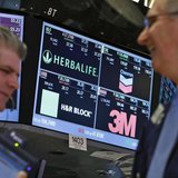 A screen displays the tickers symbols for; Herbalife, Chevron, H&R Block and 3M as traders work on the floor at the New York Stock Exchange, A screen displays the tickers symbols for; Herbalife, Chevron, H&R Block and 3M as traders work on the floor at the New York Stock Exchange,