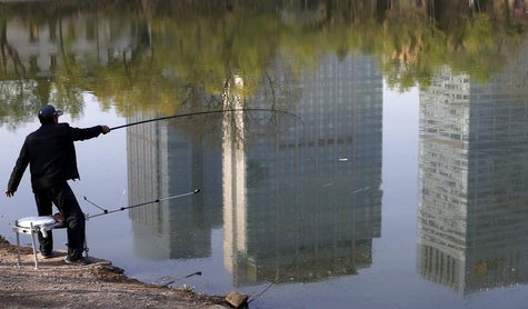 A man fishes next to a lake with the reflection of newly-built residential buildings at a park in Shenyang, Liaoning province, April 16, 201 A man fishes next to a lake with the reflection of newly-built residential buildings at a park in Shenyang, Liaoning province, April 16, 201